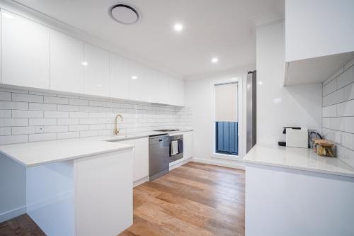 a white kitchen with white countertops and a window at Elegance and Style in Wagga Wagga