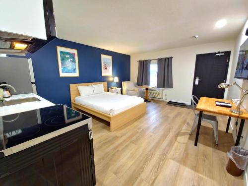 a bedroom with a bed and a kitchen with a sink at Cloud 9 Inn in Whitecourt