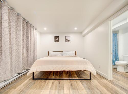 a white bedroom with a bed and a toilet at Cozy & Luxurious 3-BR condo (4min to metro) in Montreal