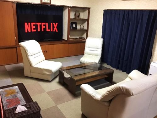 a living room with white chairs and a television at Nikko World Heritage STAY【日光山内】一棟丸貸しの宿 in Nikko