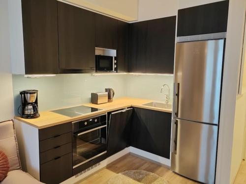 a kitchen with black cabinets and a stainless steel refrigerator at Upea yksiö ydinkeskustasta. in Lappeenranta