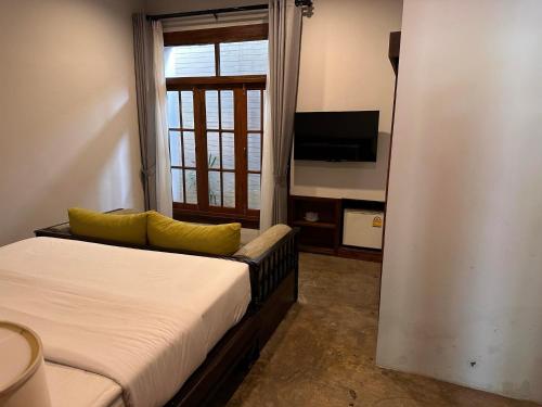 a bedroom with a bed and a tv and a window at Baan Yaimai Boutique Samui in Bophut 