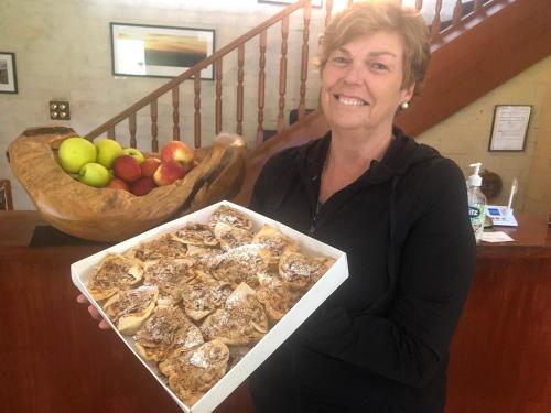a woman holding a box of food with a bowl of fruit at Girraween Country Inn in Ballandean