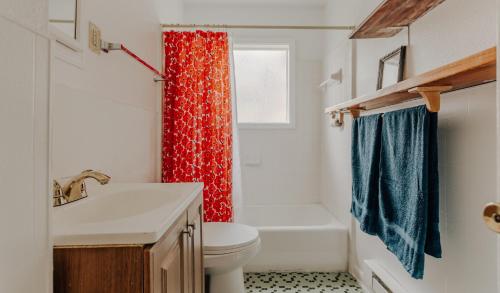 a bathroom with a white toilet and a red shower curtain at Visit for Formula 1, Stay at Magic Tree House at UT, Dtwn in Austin