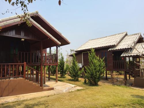 una casa con porche y un edificio con árboles en Rai Phuchat, en Ban Pa Thon