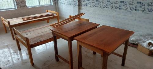 2 mesas de madera y bancos en una habitación en MAA PG, en Silchar