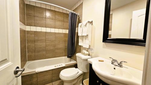 a bathroom with a toilet and a sink and a tub at Cloud 9 Inn in Whitecourt