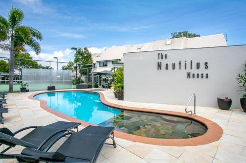 a swimming pool with chairs and a building at Nautilus Noosa Resort in Noosaville