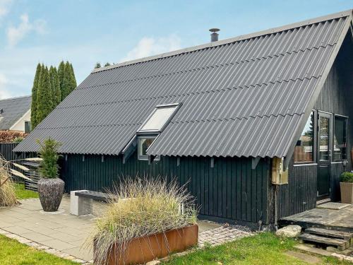 a black house with a metal roof at 4 person holiday home in Karreb ksminde in Karrebæksminde