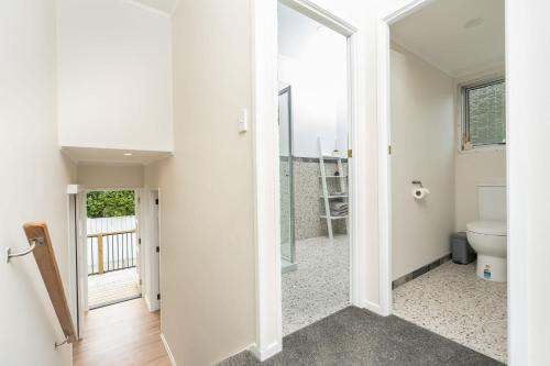 a bathroom with a toilet and a glass door at Riverside Retreat in Whangarei