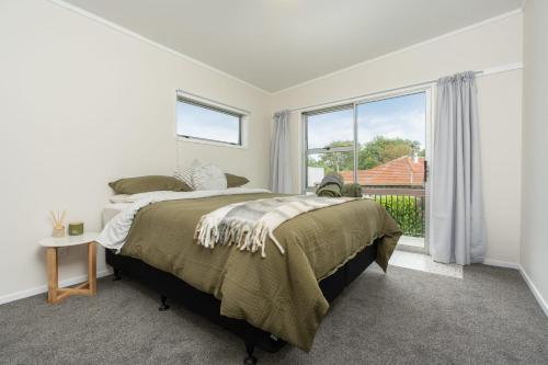 um quarto com uma cama e uma grande janela em Riverside Retreat em Whangarei