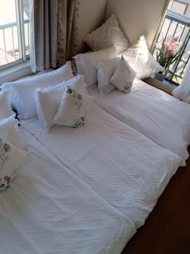 a large white bed with pillows and a window at Tokyo downtown芍藥莊 in Tokyo