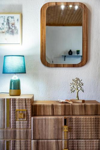 a mirror above a dresser with a lamp on it at Blossom Apartment in Skopelos Town
