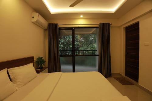 a bedroom with a bed and a large window at VV ROOMS cochin internationalairport in Nedumbassery