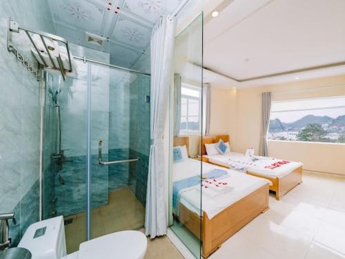 uma casa de banho com 2 camas e uma cabina de duche em vidro. em Lang Chai Hotel - Travel Agency em Ilha de Cát Bà