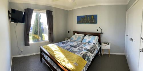 a bedroom with a bed with a television and a window at Unit 9 Bellevue in Lakes Entrance