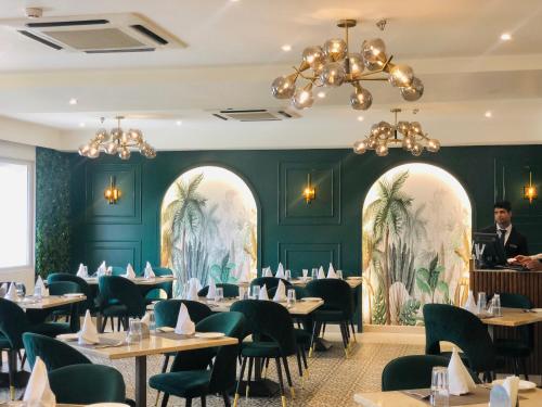 a dining room with tables and chairs and green walls at Grand Plaza Lords Inn Jammu in Jammu