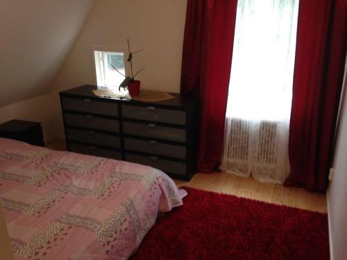 a bedroom with a bed and a dresser and a window at 2 Bedrooms apartment in a villa, close to nature. in Västerås