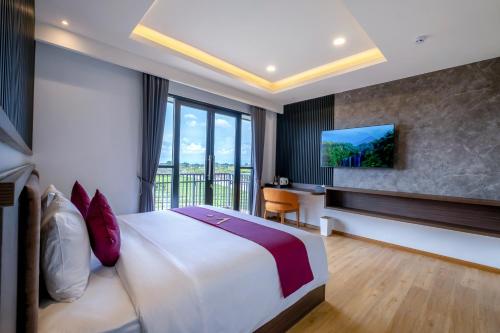 a hotel room with a large bed and a tv at ValStar Hotel Canggu in Canggu