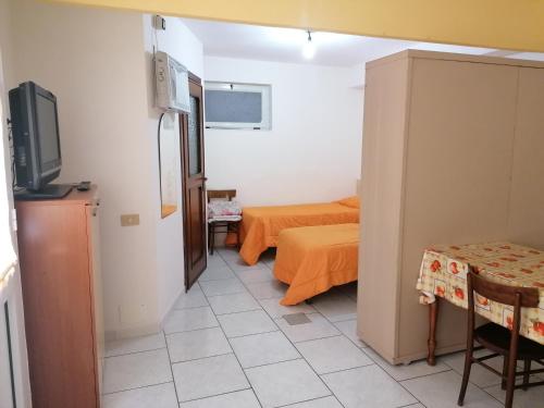 een kleine kamer met 2 bedden en een televisie bij Monolocale 3 letti con cucina e parcheggio gratuito in Candela
