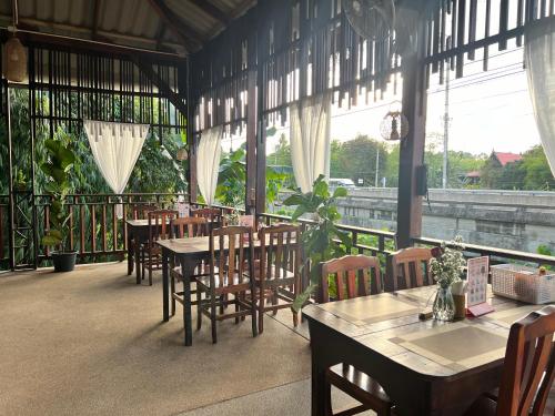 - une salle à manger avec des tables, des chaises et des fenêtres dans l'établissement Garden Villa Khaolak, à Khao Lak