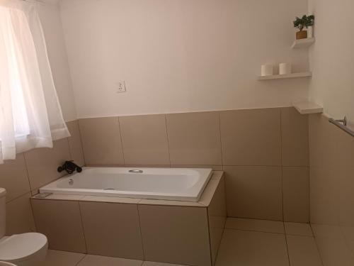 La salle de bains est pourvue d'une baignoire et de toilettes. dans l'établissement Khaya Mnandi Leisure Suites, à Pretoria