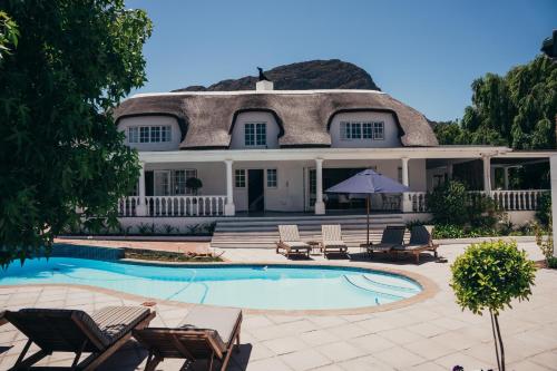 a house with a thatched roof and a swimming pool at Mirabelle Guesthouse in Franschhoek