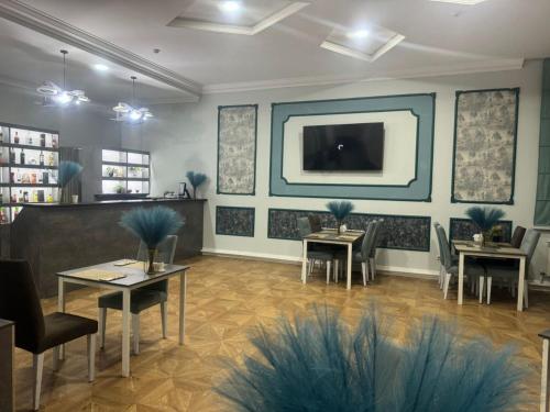 un restaurante con mesas y sillas y TV en la pared en Merdan Hotel en Zaozërnyy