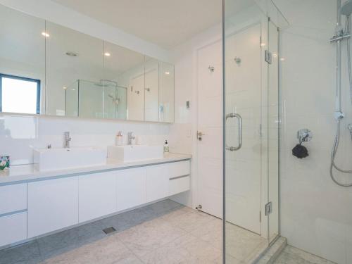a white bathroom with a sink and a shower at Tairua Marina Villa in Tairua