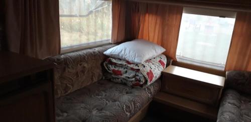 un sofá con 2 almohadas junto a 2 ventanas en Noclegi u Janinki - LISICA en Ostrowiec Świętokrzyski