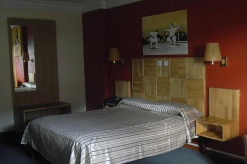 Le Saint Georges Hotel في بورت لويس: غرفة نوم بسرير ومرآة