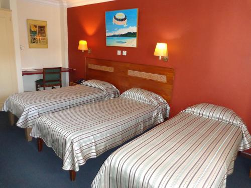 2 Betten in einem Hotelzimmer mit roten Wänden in der Unterkunft Le Saint Georges Hotel in Port Louis