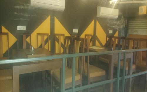 a row of wooden tables and chairs in a room at HOTEL CHETRAM ELITE near railway station in Jaipur