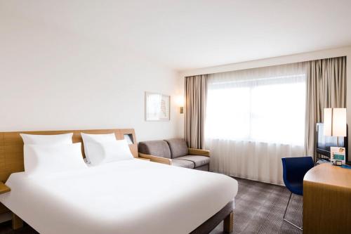een groot wit bed in een hotelkamer bij Novotel Aachen City in Aken