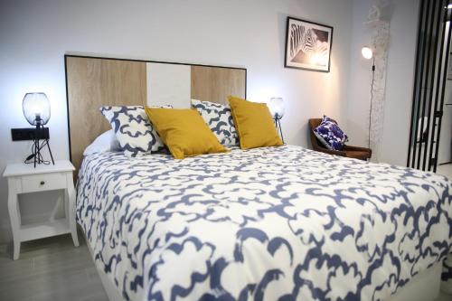 a bedroom with a large bed with yellow and blue pillows at E&R-1 Plaza España in Salamanca