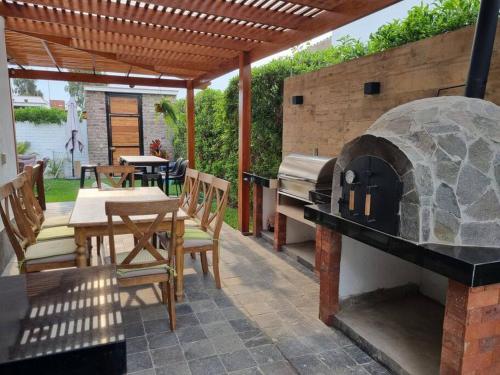 un patio con un horno al aire libre con mesas y sillas en Casa Gardenias - Condominio Privado en Asia, en Asia