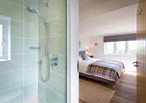 a bathroom with a shower and a bed in a room at Morannedd in Abersoch