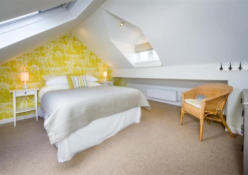 a bedroom with a large bed and a chair at Morannedd in Abersoch