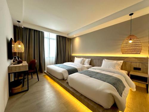 una camera d'albergo con 2 letti e una scrivania di Theatre Hotel a Kuching