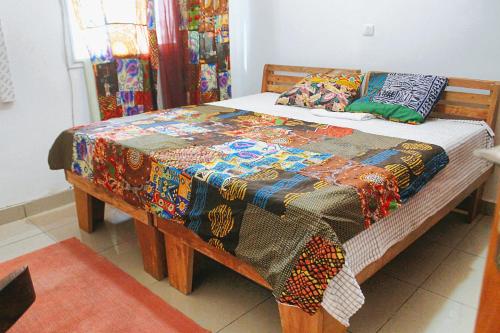 a bed with a colorful blanket on top of it at Galerie d'hôte la Martine in Kribi