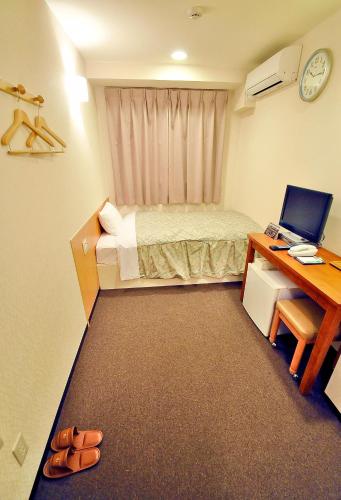 a small room with a bed and a desk with a computer at Okayama Universal Hotel Annex 2 in Okayama