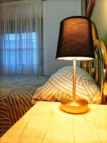 a lamp sitting on a table next to a bed at Hostal Restaurante Solaire in Castañar de Ibor