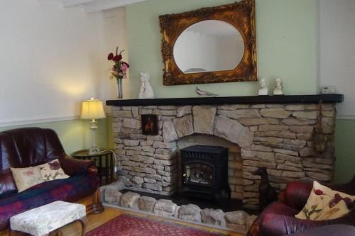 un soggiorno con camino in pietra e specchio di The Weaver's Cottage a Dungannon