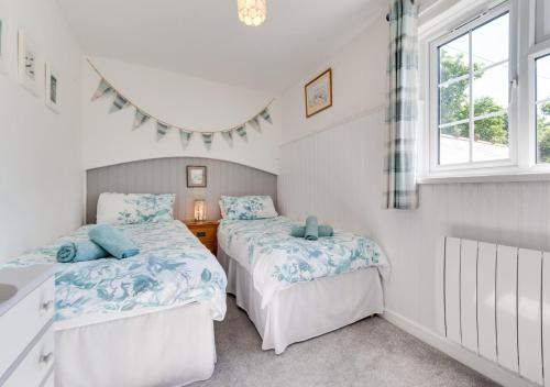 a bedroom with two beds and a window at Coverack Cottage in Saint Keverne