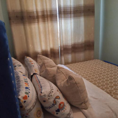 a bed with pillows on it next to a window at Verona Apartments in Thika