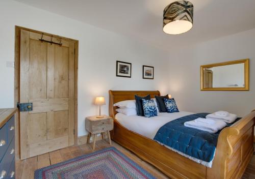 a bedroom with a wooden bed with a wooden door at Higher Treliver Farmhouse in Saint Wenn