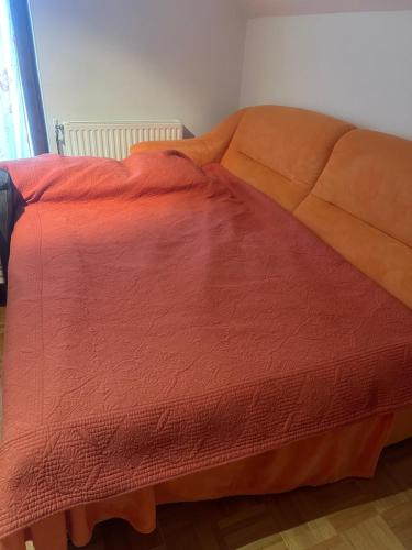a bed with an orange comforter in a room at ZIDANICA MEDLE in Otočec