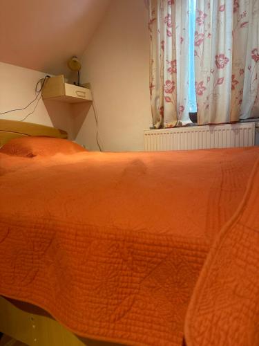 a bed with an orange comforter in front of a window at ZIDANICA MEDLE in Otočec