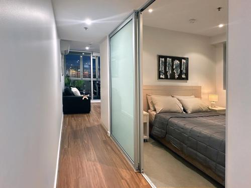 een slaapkamer met een bed en een glazen schuifdeur bij CBD Penthouse View Apartment in Adelaide