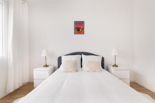 a white bedroom with a white bed with two night stands at Apparemment Cosy Paris CDG Stade Expo in Aulnay-sous-Bois